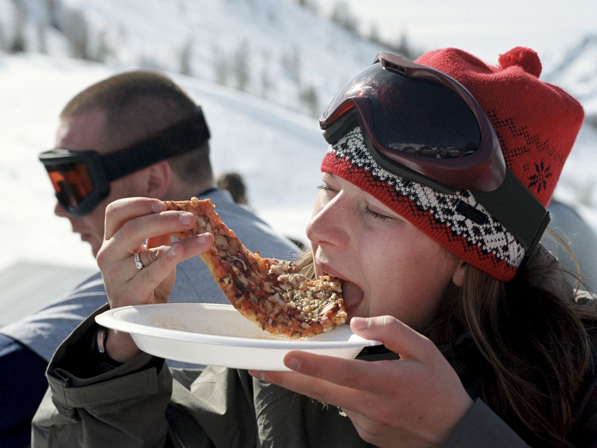 person eating pizza in the snow